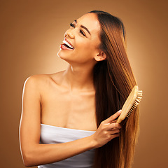 Image showing Brushing hair, beauty and a happy woman in studio for growth and color shine or healthy texture. Aesthetic female smile for brush, natural haircare and hairdresser or salon on brown background