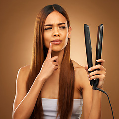 Image showing Hair, thinking and woman with flat iron for beauty, wellness and keratin treatment on brown background. Hairdresser mockup, salon and confused girl for healthy growth, haircare texture and cosmetics