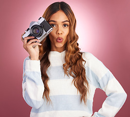 Image showing Camera, portrait and woman in studio for photography, wow and surprised against pink background. Lens, photographer and face of girl posing, whistle or emoji while posing for photo on isolated mockup