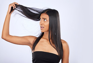 Image showing Hair damage, breakage and shock of a frustrated woman isolated on a white background in studio. Bad, unhappy and an Indian girl sad about split ends, holding tangled hairstyle and frizzy haircare