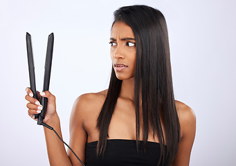 Image showing Angry, woman or hair straightener for beauty self care or treatment in studio on white background. Unhappy, frustrated Indian girl model or salon equipment for ironing in grooming routine for styling