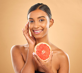 Image showing Skincare, portrait and a woman with a grapefruit for a glow isolated on a studio background. Food, smile and an Indian model with a fruit for healthy skin, complexion and vitamin c treatment