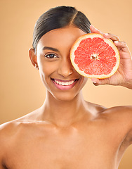 Image showing Face smile, skincare and woman with grapefruit in studio isolated on a brown background. Portrait, natural cosmetics and happy Indian female model with citrus fruit for vitamin c, nutrition or beauty