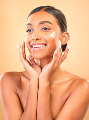 Image showing Face, skincare smile and woman with cream in studio isolated on a brown background. Dermatology cosmetics, thinking and happy Indian female model apply lotion, creme and moisturizer for healthy skin.