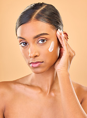 Image showing Face portrait, skincare and woman with cream in studio isolated on brown background. Dermatology, serious cosmetics and confident Indian female model with lotion, creme or moisturizer for skin health