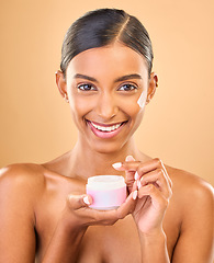 Image showing Face, skincare and woman with cream jar in studio isolated on a brown background. Dermatology cosmetics, portrait and happy Indian female apply lotion, creme and moisturizer product for healthy skin.