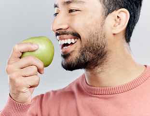 Image showing Enjoying, happy and an Asian man eating an apple isolated on a white background in a studio. Smile, food and a Chinese guy taking a bite from a fruit for nutrition, diet or hungry on a backdrop