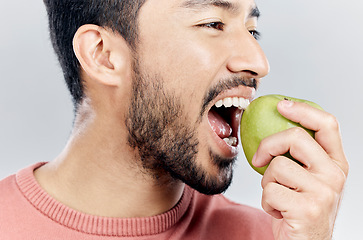 Image showing Man is eating apple, health and nutrition with fruit, diet with healthy food and wellness on studio background. Closeup, vegan male and detox with weight loss, healthcare and organic fruits