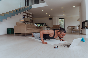 Image showing Training At Home. Sporty man doing training while watching online tutorial on laptop, exercising in living room, free space