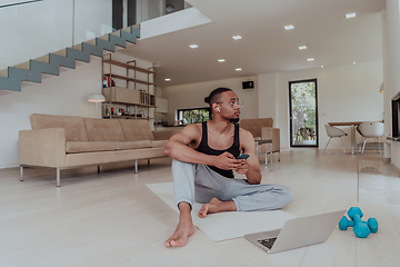 Image showing Training At Home. Sporty man doing training while watching online tutorial on laptop, exercising in living room, free space.