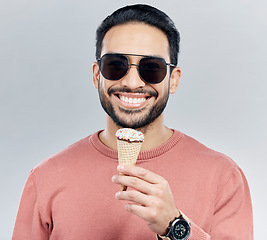 Image showing Portrait, sunglasses and ice cream with a man in studio on a gray background enjoying a sweet snack in summer. Food, fashion and dessert with a handsome young male eating or licking an icecream cone