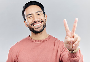 Image showing Portrait, smile and Asian man with peace sign in studio isolated on a gray background. Face, v emoji and happy, smiling or excited, young and confident male model with hand gesture or peaceful symbol