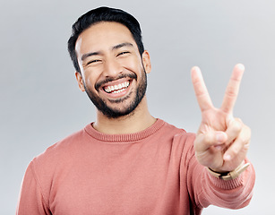 Image showing Portrait, peace sign and laughing Asian man in studio isolated on a gray background. Face, v emoji and happy, smiling or funny, young and confident male model with hand gesture or peaceful symbol.