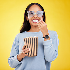 Image showing Woman is eating popcorn, watching tv and happy in portrait with snack for movie on yellow studio background. Streaming service, cinema and food with corn treat, female smile with funky sunglasses