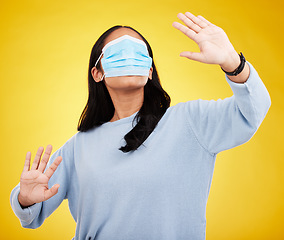Image showing Face mask, covid and woman in blindfold in studio for medical misinformation or conspiracy theory. Deception, virus and female isolated on yellow background for vaccine, protection or pandemic safety