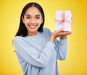 Image showing Woman smile, portrait and gift box in a studio happy from surprise present for birthday. Giveaway prize, isolated and yellow background of a young female student feeling positive and cheerful