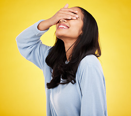 Image showing Happy, hands cover eyes and woman with smile in yellow studio for positive mindset, happiness and freedom. Fashion, mockup space and isolated girl with hand on face for surprise, emoji and reaction