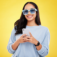 Image showing Phone, smile and portrait of woman with sunglasses in yellow studio for social media, website and internet. Communication, mockup space and happy girl on smartphone for chat, message and network