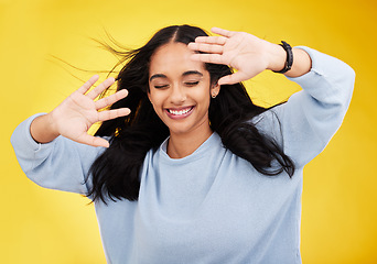 Image showing Happy, wind and face of woman with hands on yellow background with smile, happiness and freedom. Hair blowing, mockup space and isolated girl with open palms for beauty, relaxing and calm in studio
