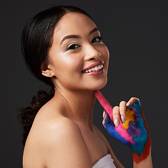 Image showing Beauty, woman and face, paint on hand with art, colorful aesthetic and happiness in portrait on studio background. Skin, glow and cosmetics with creativity and female with smile, fashion and creative