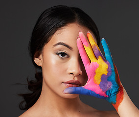 Image showing Beauty, woman and face, paint on palm with art, colorful aesthetic and makeup with color in portrait on studio background. Skin, glow and cosmetics, creativity and female hand with artistic