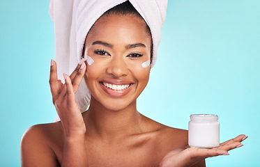 Image showing Skincare, beauty and portrait of black woman with cream, towel and smile in bathroom routine or skin glow on blue background. Cosmetics, facial and African model with lotion product in hand in studio