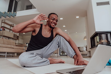 Image showing Training At Home. Sporty man doing training while watching online tutorial on laptop, exercising in living room, free space