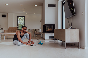 Image showing Training At Home. Sporty man doing training while watching online tutorial on laptop, exercising in living room, free space