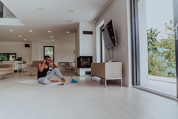 Image showing Training At Home. Sporty man doing training while watching online tutorial on laptop, exercising in living room, free space