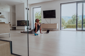 Image showing Training At Home. Sporty man doing training while watching online tutorial on laptop, exercising in living room, free space