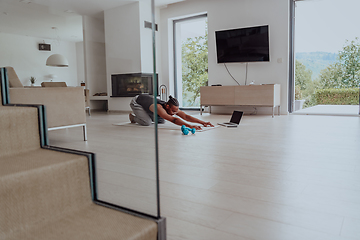 Image showing Training At Home. Sporty man doing training while watching online tutorial on laptop, exercising in living room, free space