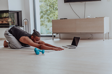 Image showing Training At Home. Sporty man doing training while watching online tutorial on laptop, exercising in living room, free space