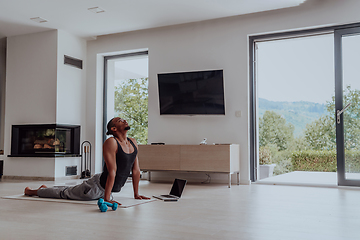 Image showing Training At Home. Sporty man doing training while watching online tutorial on laptop, exercising in living room, free space