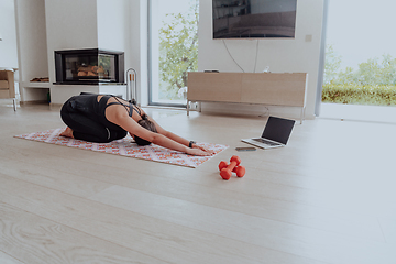 Image showing Young Beautiful Female Exercising, Stretching and Practising Yoga with Trainer via Video Call Conference in Bright Sunny House. Healthy Lifestyle, Wellbeing and Mindfulness Concept.