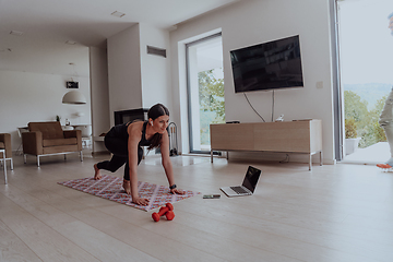 Image showing Young Beautiful Female Exercising, Stretching and Practising Yoga with Trainer via Video Call Conference in Bright Sunny House. Healthy Lifestyle, Wellbeing and Mindfulness Concept.