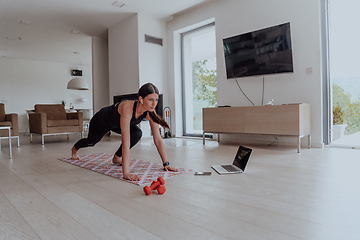 Image showing Young Beautiful Female Exercising, Stretching and Practising Yoga with Trainer via Video Call Conference in Bright Sunny House. Healthy Lifestyle, Wellbeing and Mindfulness Concept.