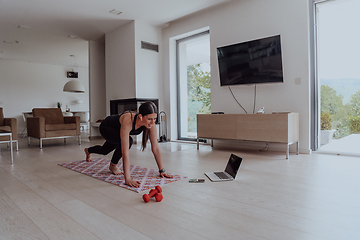 Image showing Young Beautiful Female Exercising, Stretching and Practising Yoga with Trainer via Video Call Conference in Bright Sunny House. Healthy Lifestyle, Wellbeing and Mindfulness Concept.