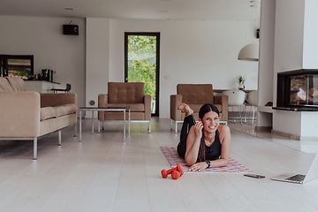 Image showing Young woman resting after online training while lying on the living room floor