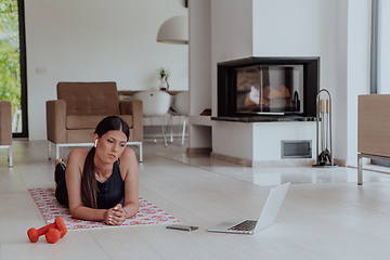 Image showing Young woman resting after online training while lying on the living room floor