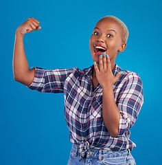 Image showing Shocked, arm flex and portrait of black woman in studio for empowerment, confident or success. Achievement, hard work and pride with female isolated on blue background for power, strong or motivation