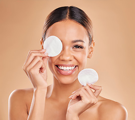 Image showing Face, cotton pad and woman with makeup, dermatology and happiness against a brown studio background. Portrait, female or lady with smile, cosmetics and organic facial with foundation remover and joy