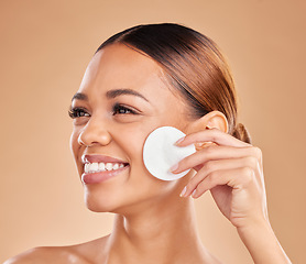 Image showing Cotton, beauty and cleaning skin of woman in studio for dermatology, cosmetic and detox. Face and smile of female with hand for natural facial makeup clean, self care and skincare on brown background