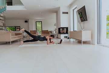 Image showing Young Beautiful Female Exercising, Stretching and Practising Yoga with Trainer via Video Call Conference in Bright Sunny House. Healthy Lifestyle, Wellbeing and Mindfulness Concept.