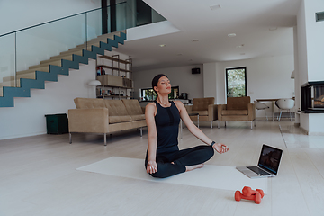 Image showing Young Beautiful Female Exercising, Stretching and Practising Yoga with Trainer via Video Call Conference in Bright Sunny House. Healthy Lifestyle, Wellbeing and Mindfulness Concept.