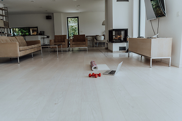 Image showing Photo of a laptop, dumbbells and headphones on the floor of the living room. Online training concept