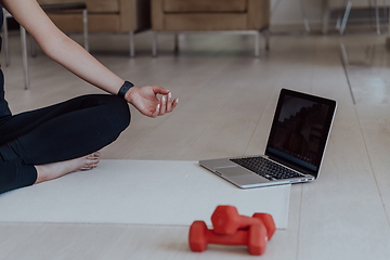 Image showing Young Beautiful Female Exercising, Stretching and Practising Yoga with Trainer via Video Call Conference in Bright Sunny House. Healthy Lifestyle, Wellbeing and Mindfulness Concept.