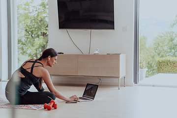 Image showing Young Beautiful Female Woman with Trainer via Video Call Conference in Bright Sunny House. Healthy Lifestyle, Wellbeing and Mindfulness Concept.