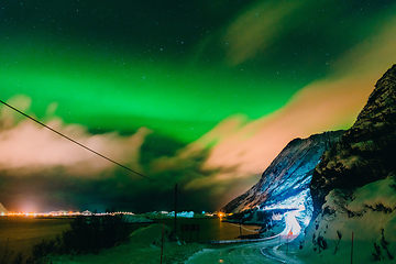 Image showing Amazing display of northern lights seen in the north with a bright green band dancing across the sky with a stunning log cabin lodge below.