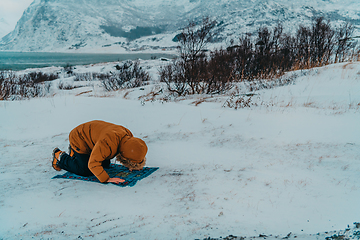 Image showing A Muslim traveling through arctic cold regions while performing the Muslim prayer namaz during breaks