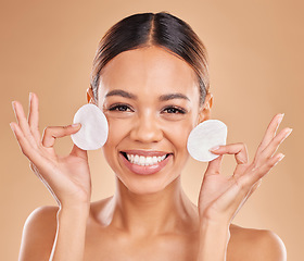 Image showing Face, dermatology and woman with cotton pad, organic facial and smile against a brown studio background. Portrait, female or lady with skincare, makeup remover and happiness with glow and smooth skin